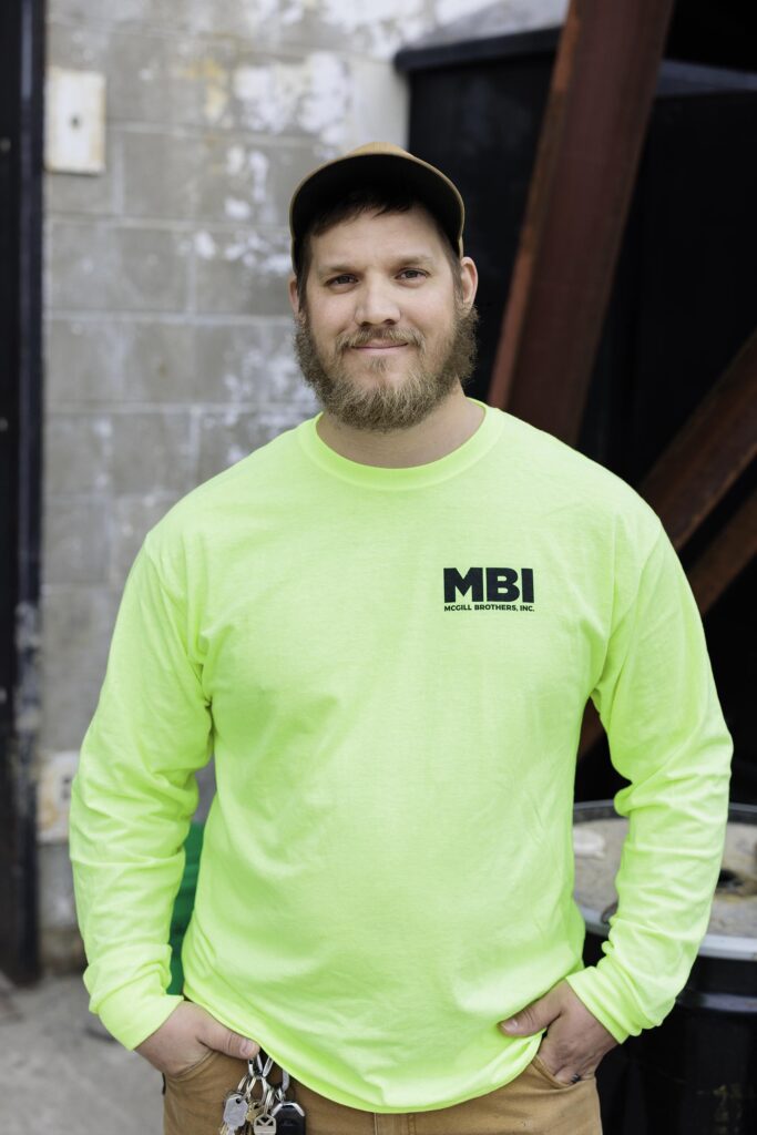 portrait of superintendant Tyler Nippart standing in from of McGill headquarters wearing a neon shirt with the MBI logo